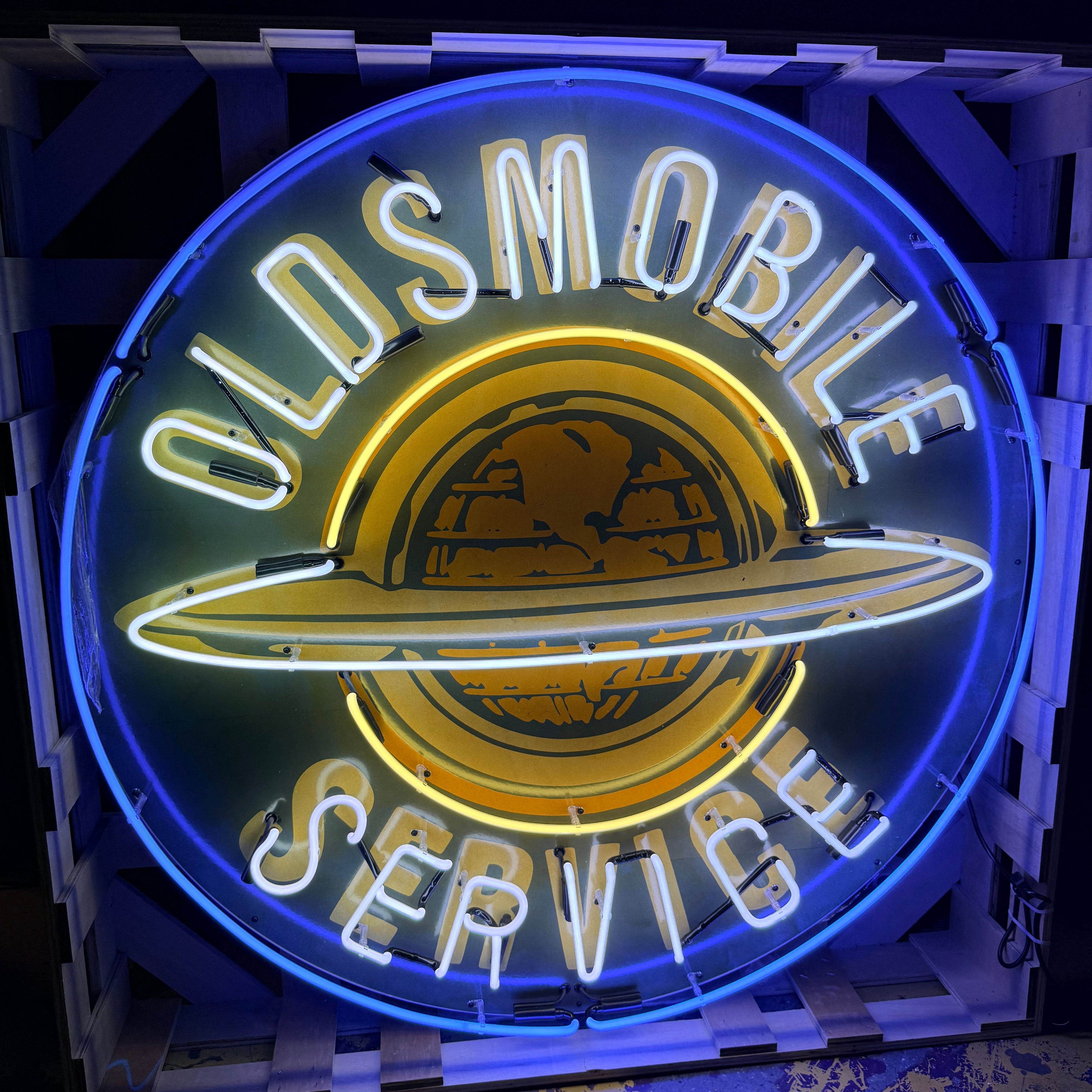 Neon sign for Oldsmobile service with blue and yellow colors.